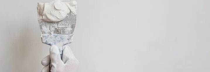 Hand mit Spachtel und Spachtelmasse